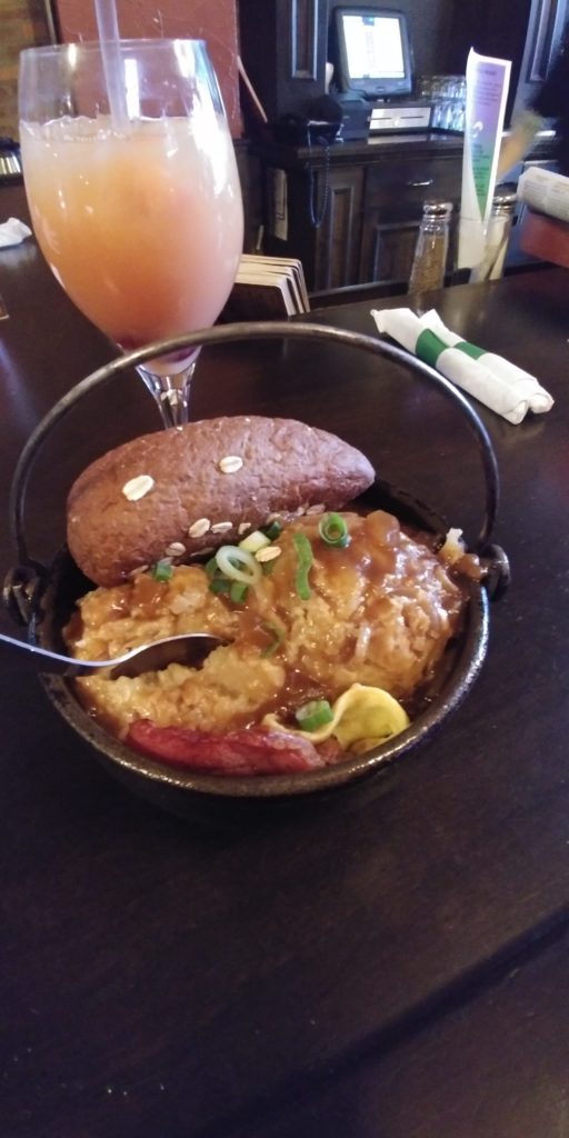 Brunch of hash browns, gravy, bacon, eggs, and bread.