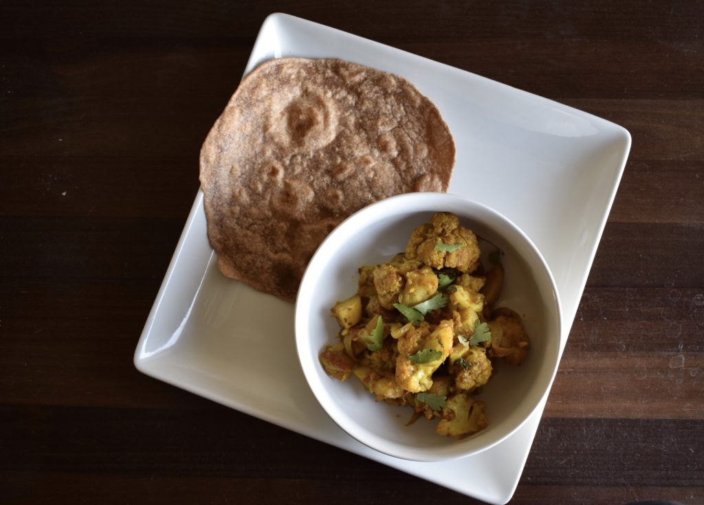 Aloo gobi Indian curried cauliflower and potatoes in a bowl with roti