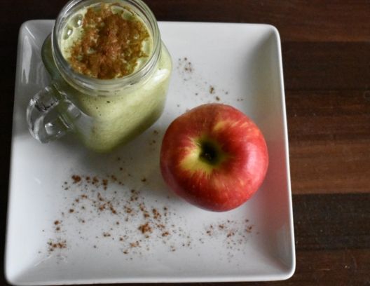 overhead shot of a mug of apple pie protein shake and an apple